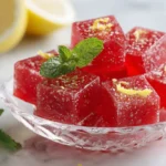 Red high-protein gelatin cubes in a glass bowl on a light surface, ideal as a sugar-free bariatric dessert.