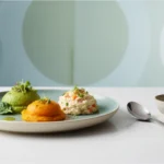 Bariatric recipes soft food three smooth vegetable purées on a sage green plate: green pea purée with microgreens, sweet potato purée, and a creamy vegetable rice salad, perfect for post-bariatric soft food diet.