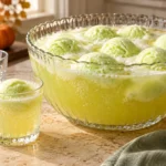 Witches brew punch with lime sherbet in a glass bowl and serving glass